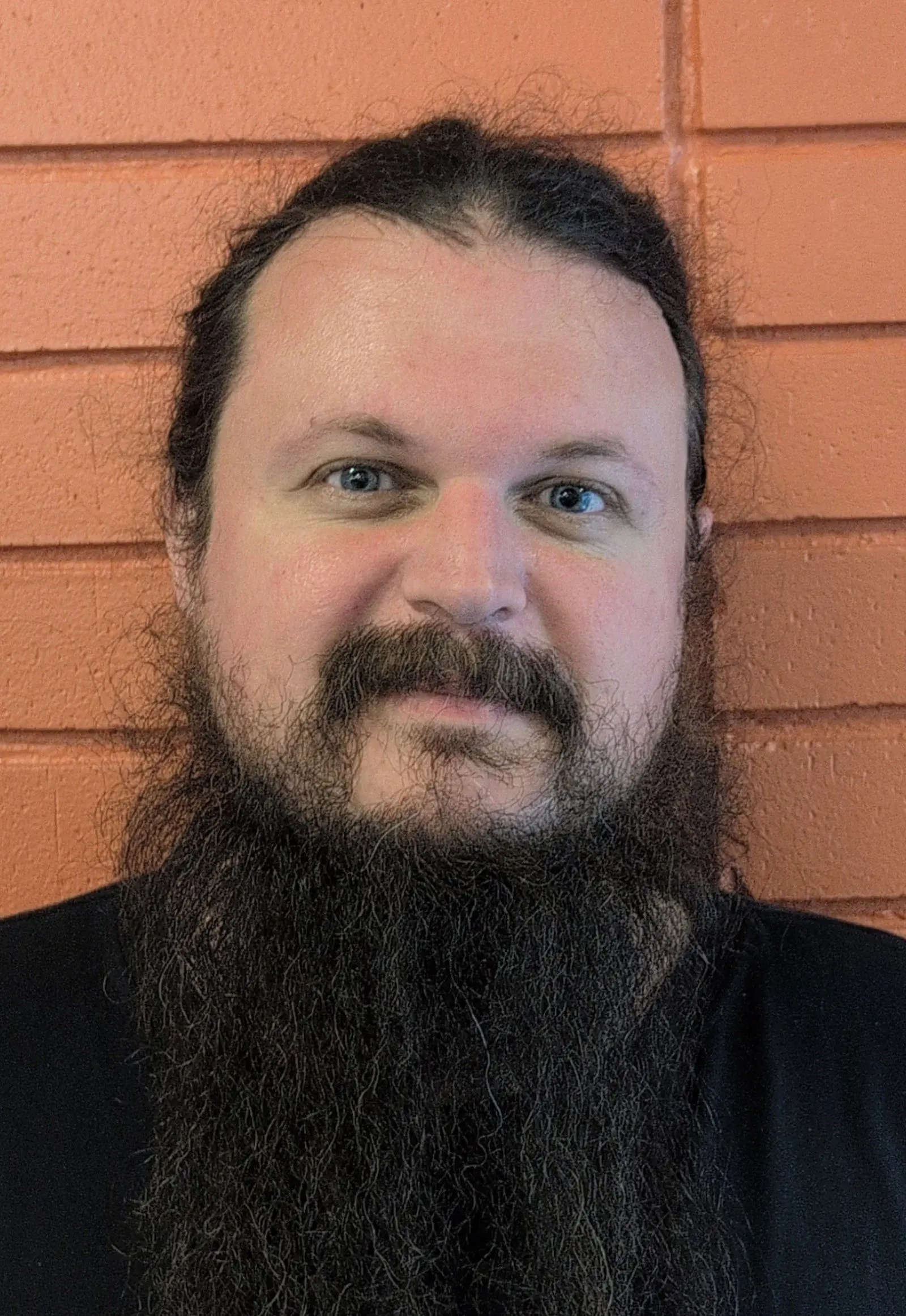 Headshot of Brandon who has a long dark beard and long hair pulled back