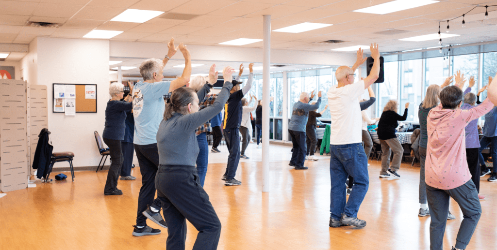 A group of people participate in a standing exercise class