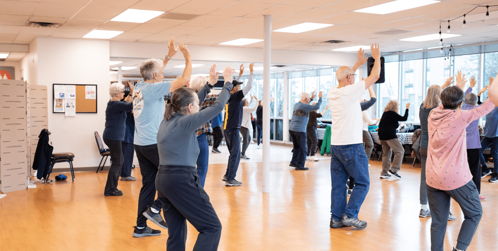 A group of people participate in a standing exercise class