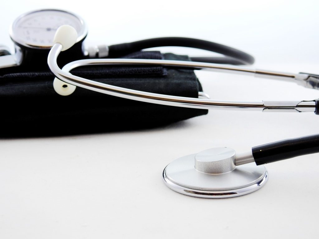 A stethoscope and a blood pressure monitor are lying on a white surface, embodying essential healthcare tools in any professional presentation.