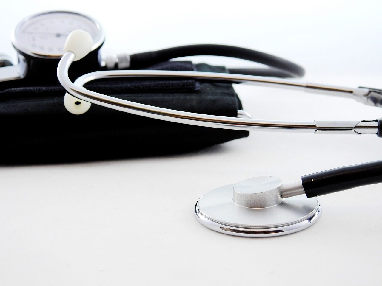 A stethoscope and a blood pressure monitor are lying on a white surface, embodying essential healthcare tools in any professional presentation.