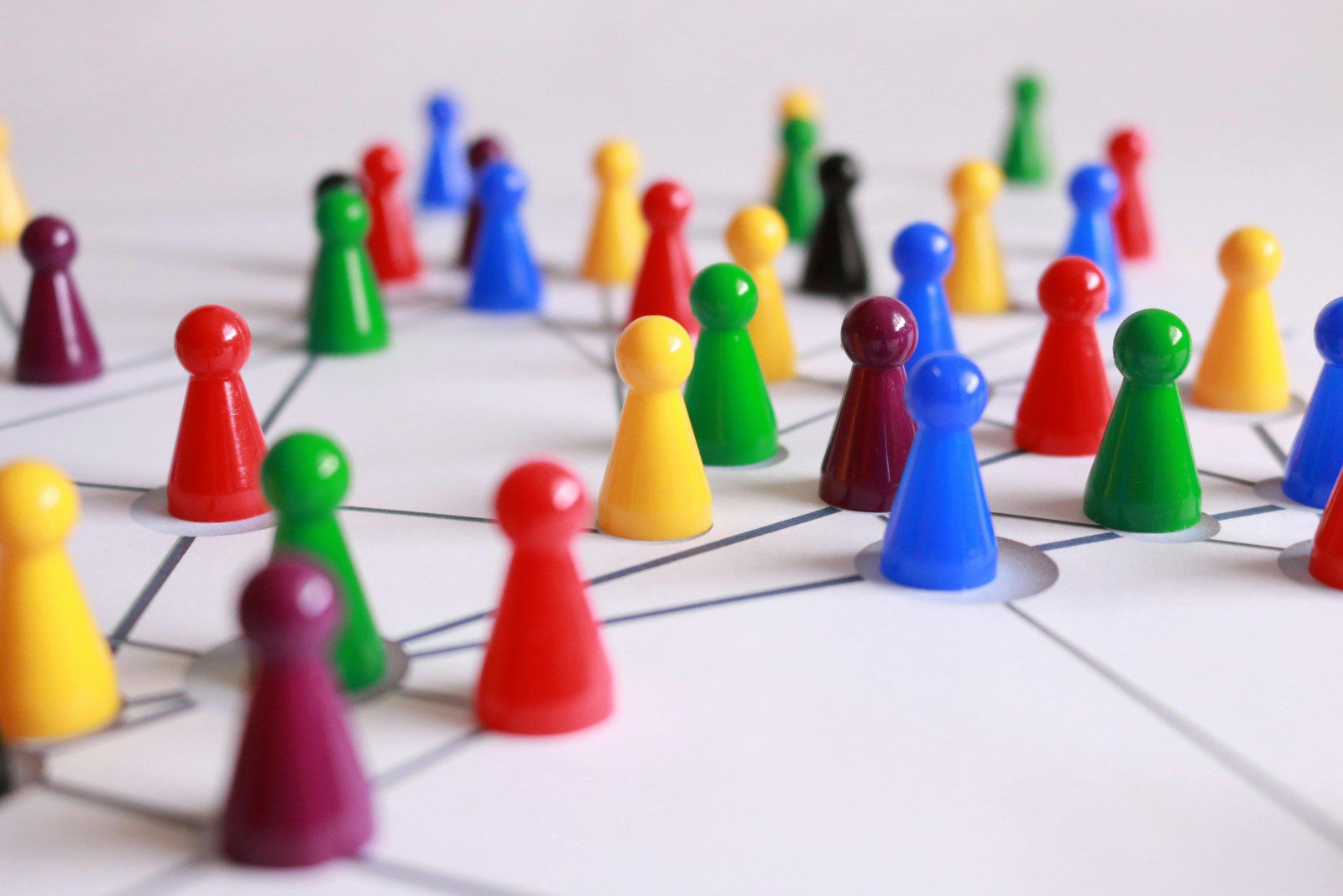 Colored game pieces are arranged on a white surface with intersecting lines, representing a network or interconnected system.