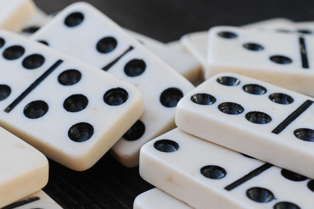 A close-up of several white domino tiles with black dots,