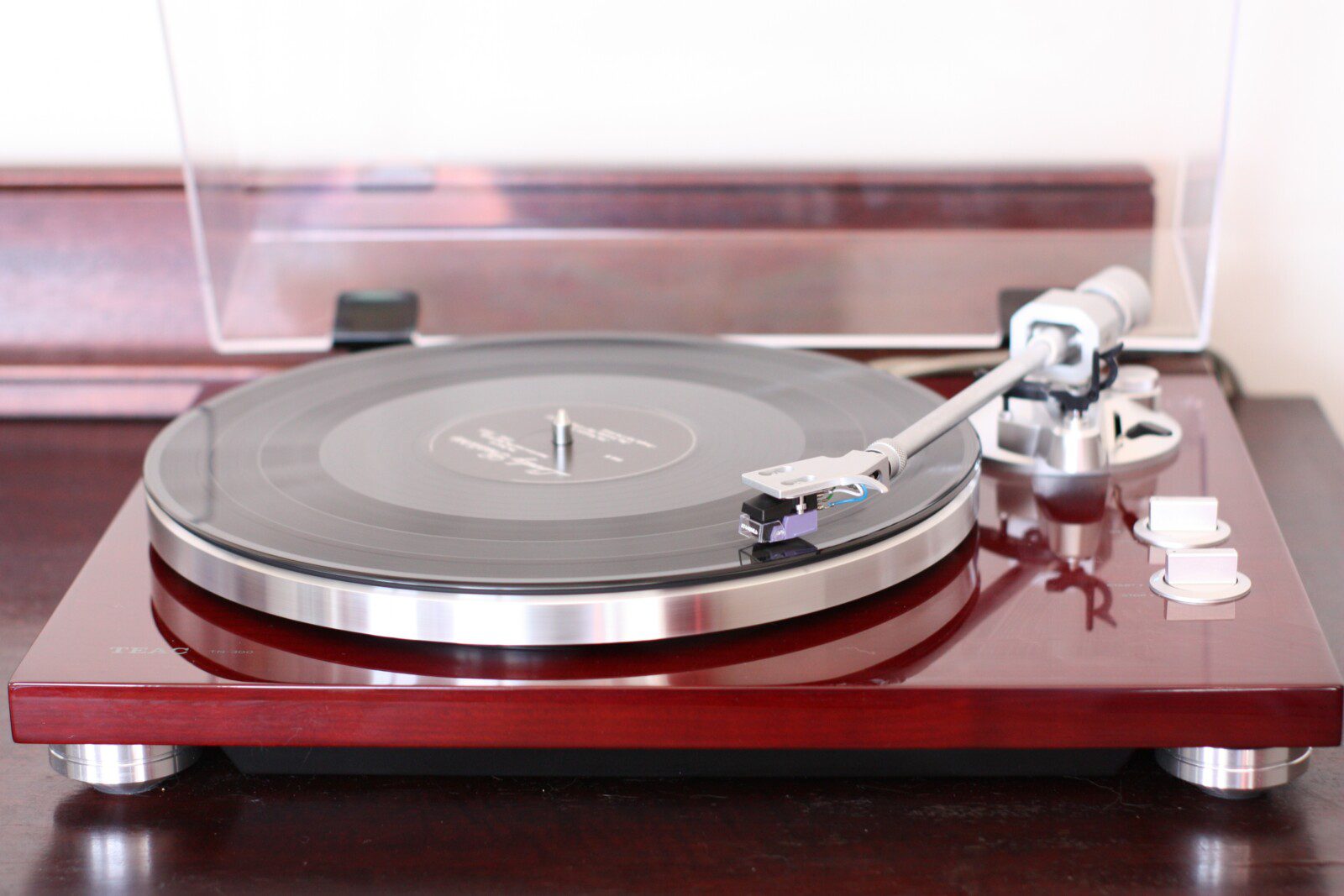 A close-up of a vinyl record player with a clear dust cover,