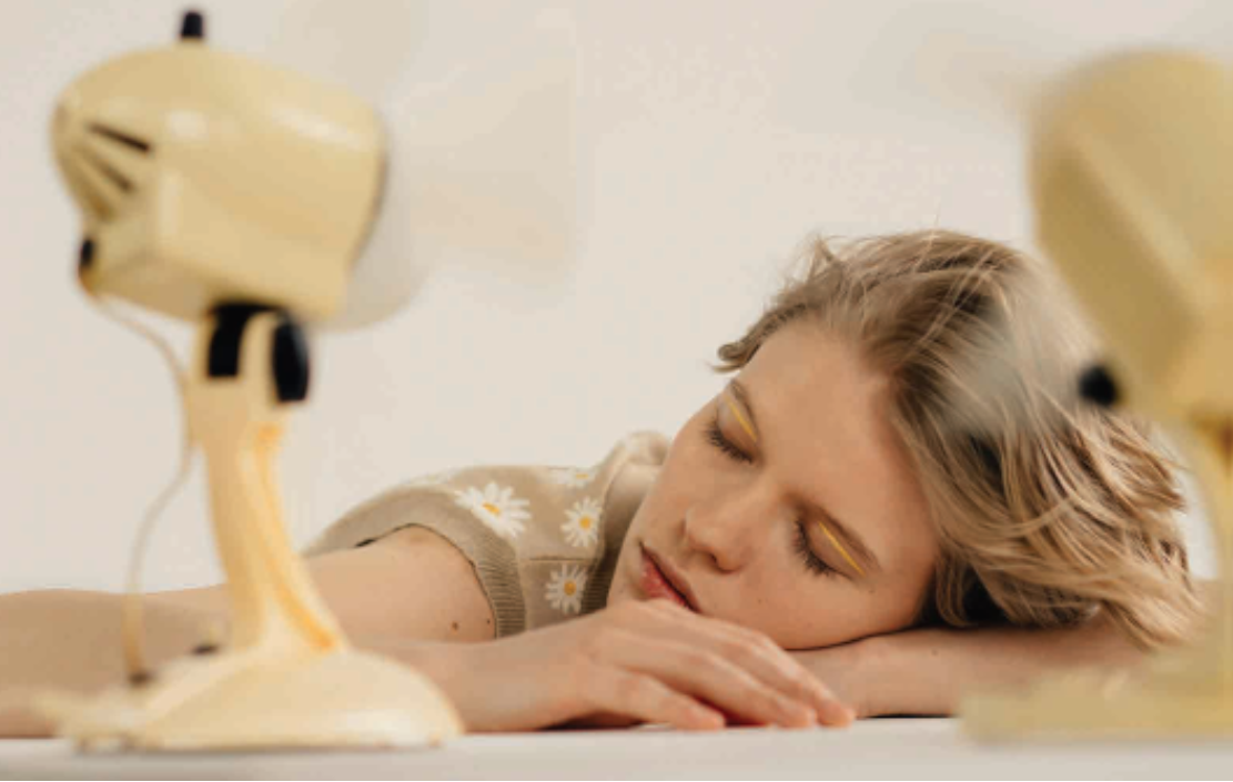 A woman with closed eyes is in front of a fan