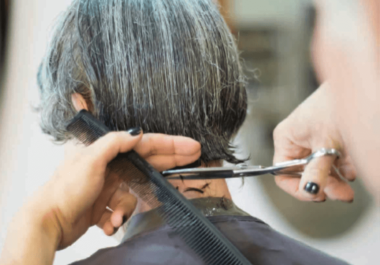 A woman with short gray hair is getting a haircut