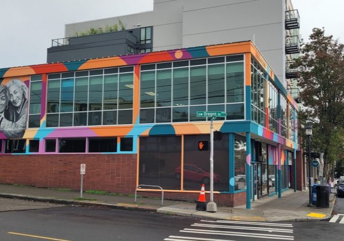 Outside of The Center with large windows, mural art of two smiling people,