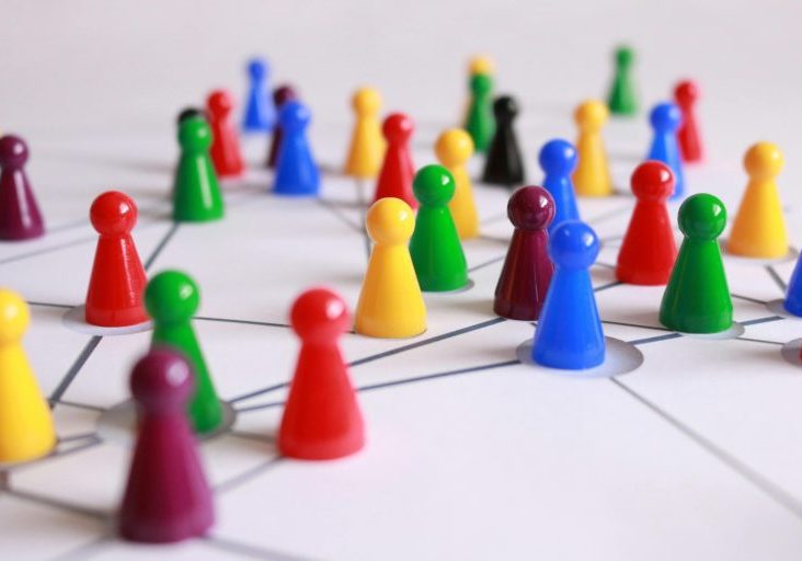 Colored game pieces are arranged on a white surface with intersecting lines, representing a network or interconnected system.